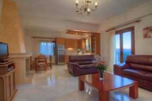 una sala de estar con 2 sofás de cuero y una mesa. en Anemomylos Villas, countryside retreats, By ThinkVilla, en Panormos Rethymno