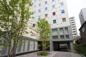 福冈CROSS Life Hakata Yanagibashi的前面有树木的白色建筑