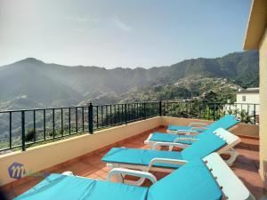 d'un balcon avec des tables et des chaises bleues et des montagnes. dans l'établissement Casa do Romaninho, à Porto da Cruz