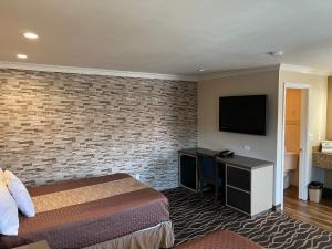a hotel room with a bed and a flat screen tv at Walnut Inn & Suites West Covina in West Covina