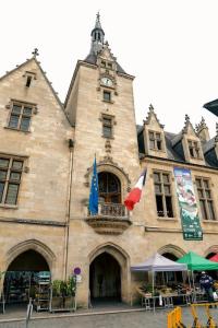 a building with a clock tower and a market in front of it at La Cloche Studio Hypercentre Mairie in Libourne