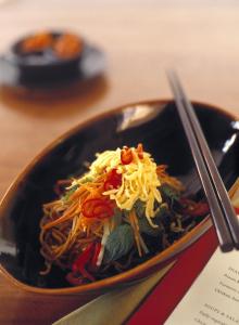 un tazón de comida con fideos y verduras en una mesa en COMO Uma Ubud en Ubud