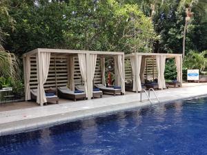a pool with chairs and a gazebo next to a swimming pool at Let's Hyde Pattaya Resort & Villas - Pool Cabanas in North Pattaya