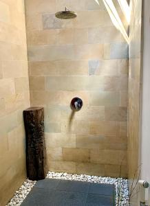um chuveiro na casa de banho com uma parede de pedra em The Yoga Garden em Gili Trawangan