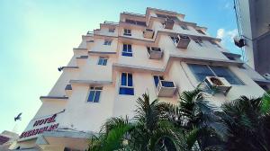 a tall white building with windows and palm trees at Dodas Palace by Asapian Hotels in Jaipur