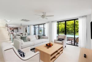 ein Wohnzimmer mit einem Sofa, Stühlen und einem Tisch in der Unterkunft Areeya Villa Layan Phuket in Phuket