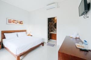 a white bedroom with a bed and a table at Nyuh Gading by The Lavana in Uluwatu