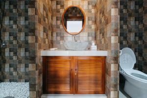 uma casa de banho com um lavatório, um espelho e um WC. em Nyuh Gading by The Lavana em Uluwatu
