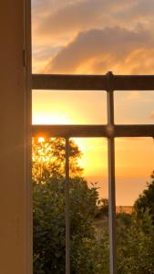 una ventana con vistas a la puesta de sol en Bakkehuset Countryhouse en Skovby