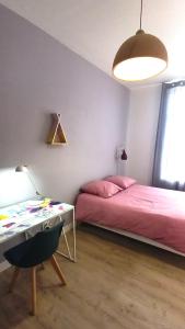 - une chambre avec un lit et un bureau avec un lit rose dans l'établissement Histoire de Loire - ANJOU sdb partagée, à Saumur