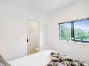 um quarto branco com uma cama e uma janela em Coastal Cabin - Whangamata Holiday Unit em Whangamata