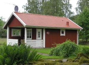 una piccola casa rossa con tetto rosso di B & B Flattinge Fritidshus a Vittaryd