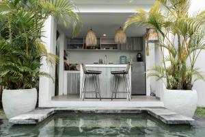 a kitchen with a bar and two chairs next to a pool at Villa Kalma Canggu in Canggu