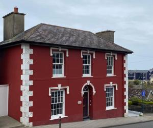 a red building with white windows on a street at Aberaeron Island House - Panoramic Harbour Views in Aberaeron