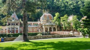 a large brick building with a tree in the foreground at Casa Arion in Băile Herculane