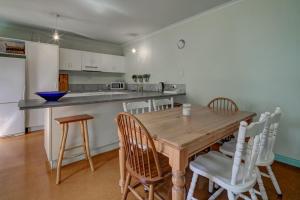 a kitchen with a wooden table and some chairs at Prues Cottage in Port Fairy