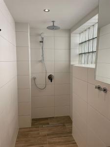 um chuveiro na casa de banho com paredes em azulejos brancos em Ferienwohnung Beutelsbacherstr. 12 C em Stuttgart