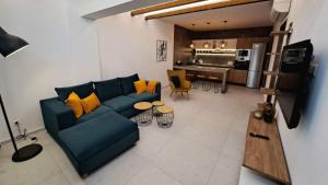 a living room with a blue couch and a kitchen at Courtyard Luxury Suites “ APOSTOLOS” in Pefki