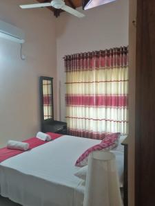 Lahiru Airport Villa في Andiambalama: غرفة نوم بسرير ابيض ونافذة