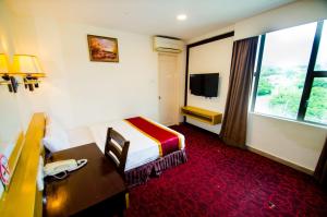 a hotel room with a bed and a desk and a window at GRAND EASTERN HOTEL SDN BHD in Kota Kinabalu