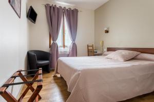 a bedroom with a bed and a chair and a window at Hotel Alienor in Brantôme