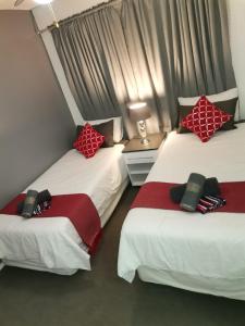 two beds with red and white pillows in a room at 42 Ramsgate palms in Margate