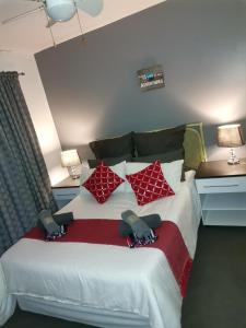 a bedroom with a large bed with red and white pillows at 42 Ramsgate palms in Margate +8 photos