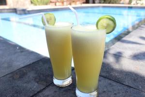 two drinks sitting on a table next to a swimming pool at Coral Beach Seaside in Gili Trawangan
