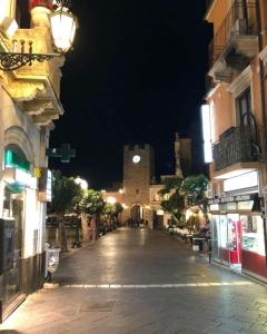 uma rua da cidade vazia à noite com uma torre do relógio em Holiday House Marlin em Giardini Naxos