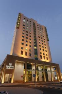 un edificio alto con luces encendidas delante de él en Dalal City Hotel, en Kuwait