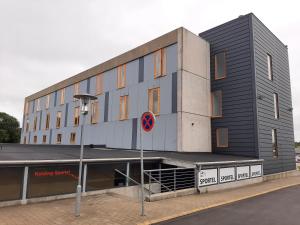 a grey building with a sign in front of it at Kolding Sportel in Kolding