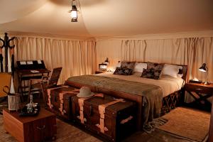 a bedroom with a bed and a table with a desk at Serengeti Pioneer Camp in Mugumu