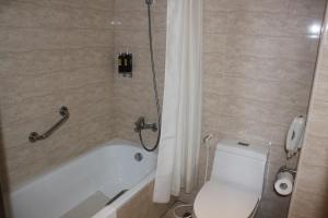 嘉義市的住宿－嘉義兆品酒店，浴室设有卫生间和带淋浴帘的浴缸。