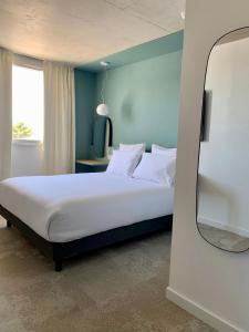 Golden Tulip Martigues Provence في مارتيغ: غرفة نوم بسرير أبيض مع مرآة