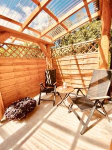 a patio with two chairs and a table and a pergola at SKALNY apartamenty, pokoje in Ogrodzieniec