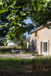 a picnic table and an umbrella in a yard at Maison d'hôtes le détour en pleine nature in Channay-sur-Lathan