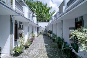 a corridor of white buildings with potted plants at Urbanview Hotel Syariah Ratu Kuring Gisting by RedDoorz in Banjarnegeri