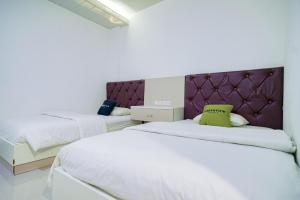 a bedroom with two beds and a purple headboard at Urbanview Hotel Syariah Ratu Kuring Gisting by RedDoorz in Banjarnegeri