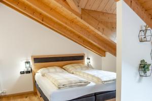 two beds in a bedroom with wooden ceilings at Apart Dolomites in Castello di Fiemme