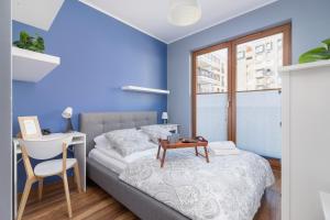 een slaapkamer met blauwe muren en een bed met een tafel bij Apartments GO Rakowicka by Noclegi Renters in Krakau +128 foto's
