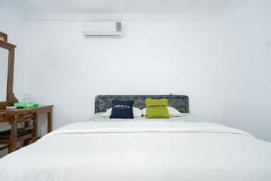 Tempat tidur dalam kamar di Urbanview Hotel Syariah Ratu Kuring Gisting by RedDoorz