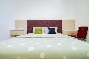 a bedroom with a large bed and a red chair at Urbanview Hotel Syariah Ratu Kuring Gisting by RedDoorz in Banjarnegeri +25 photos