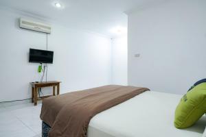 a white bedroom with a bed and a television at Urbanview Hotel Syariah Ratu Kuring Gisting by RedDoorz in Banjarnegeri