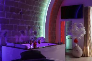 ein Wohnzimmer mit lilafarbener Beleuchtung und Ziegelwand in der Unterkunft Relax Santa Cecilia in Gravina in Puglia