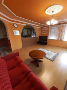 un soggiorno con divano rosso e tavolo di Gábor Pál 1 Apartman 1 szoba a Dunaföldvár