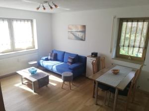 uma sala de estar com um sofá azul e uma mesa em Ferienwohnung und Sommerhaus unter der Burg em Falkenberg