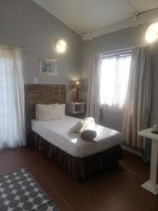 sypialnia z łóżkiem z białą pościelą i oknem w obiekcie The Old Mill Hotel w mieście Machadodorp
