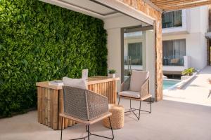 eine Terrasse mit 2 Stühlen, einem Tisch und einer grünen Wand in der Unterkunft Soho Exclusive Suites in Skala Potamias