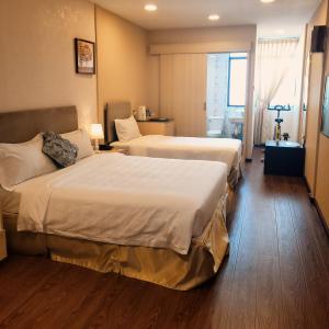 a hotel room with two beds and a window at Coconut Bay Lodge - Beribi in Bandar Seri Begawan