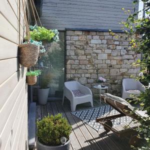 un patio con 2 sillas, una mesa y una pared de ladrillo en B&B Maison Pierreuse, en Sart-lez-Spa